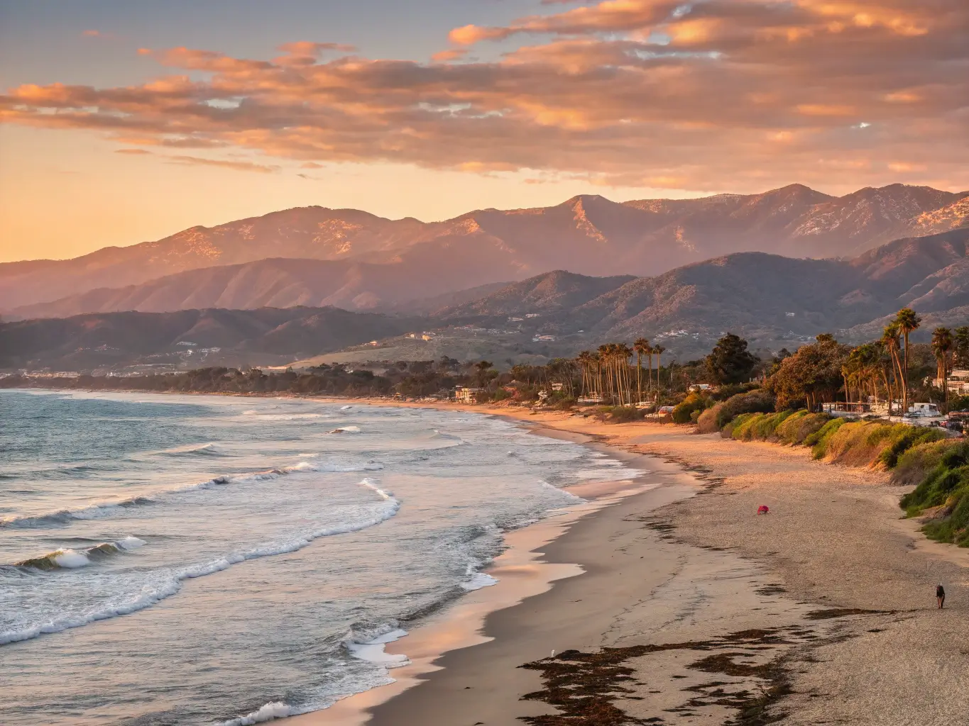 Golden-hour photograph of Santa Barbara's coastline with soft sunlight on sandy beach and azure ocean, distant mountains under September sky