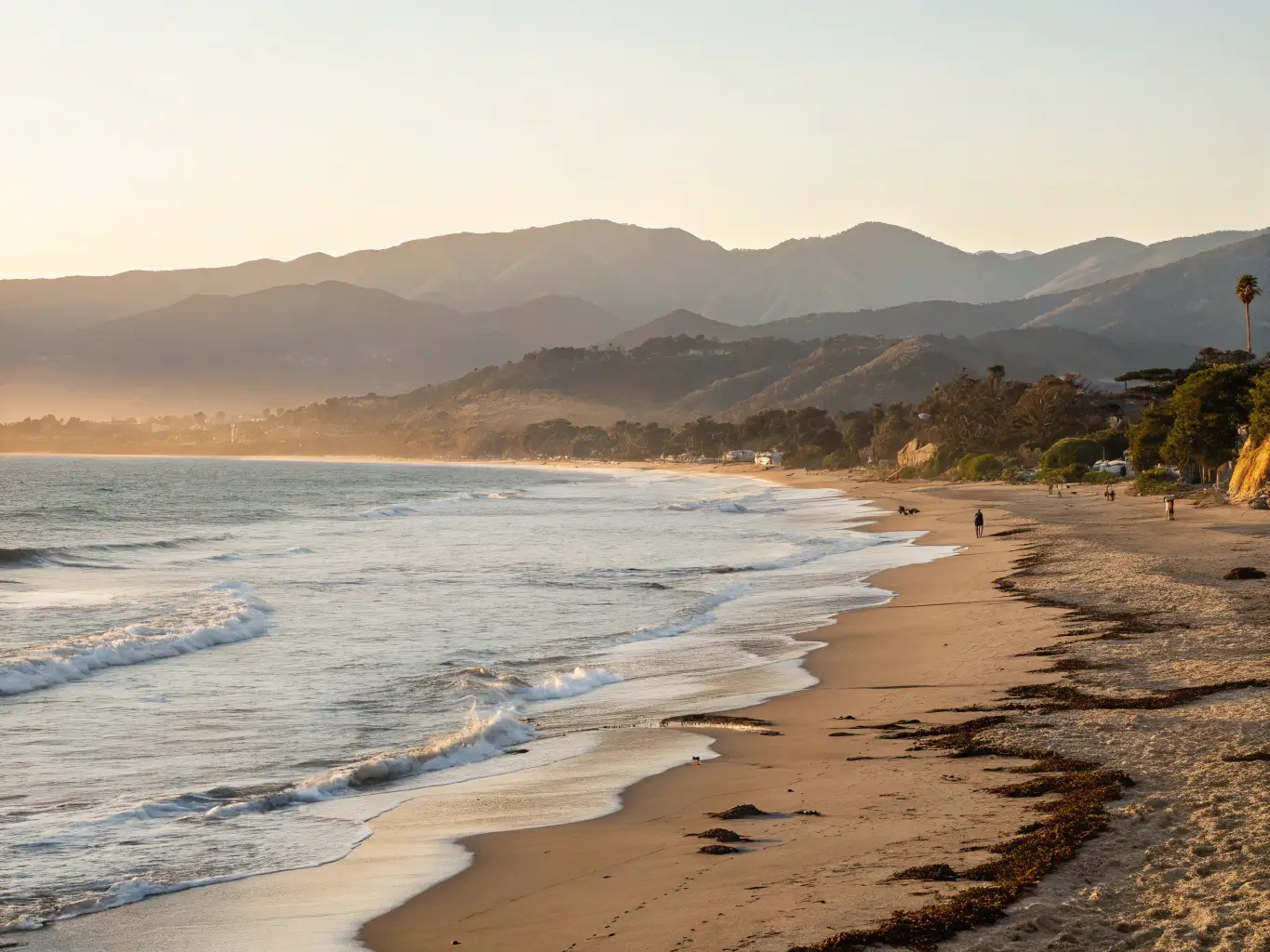 Santa Barbara coastline at dawn with golden light, calm waves, and distant mountains, no people in sight