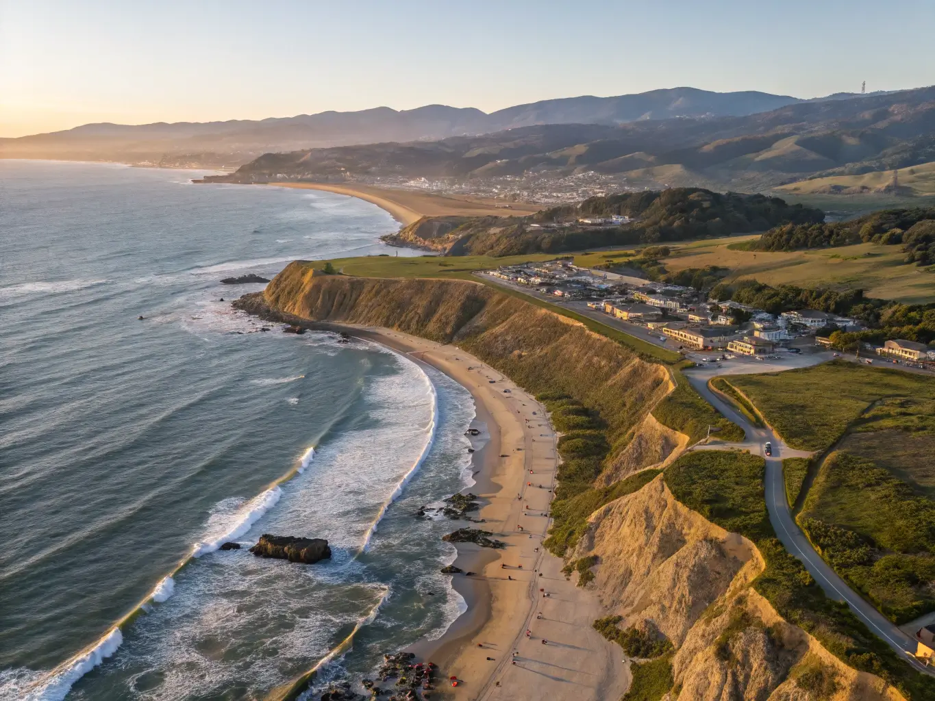Golden sunset at Half Moon Bay State Beach with warm light reflecting on sandy shores, rugged cliffs, and Pacific Ocean waves