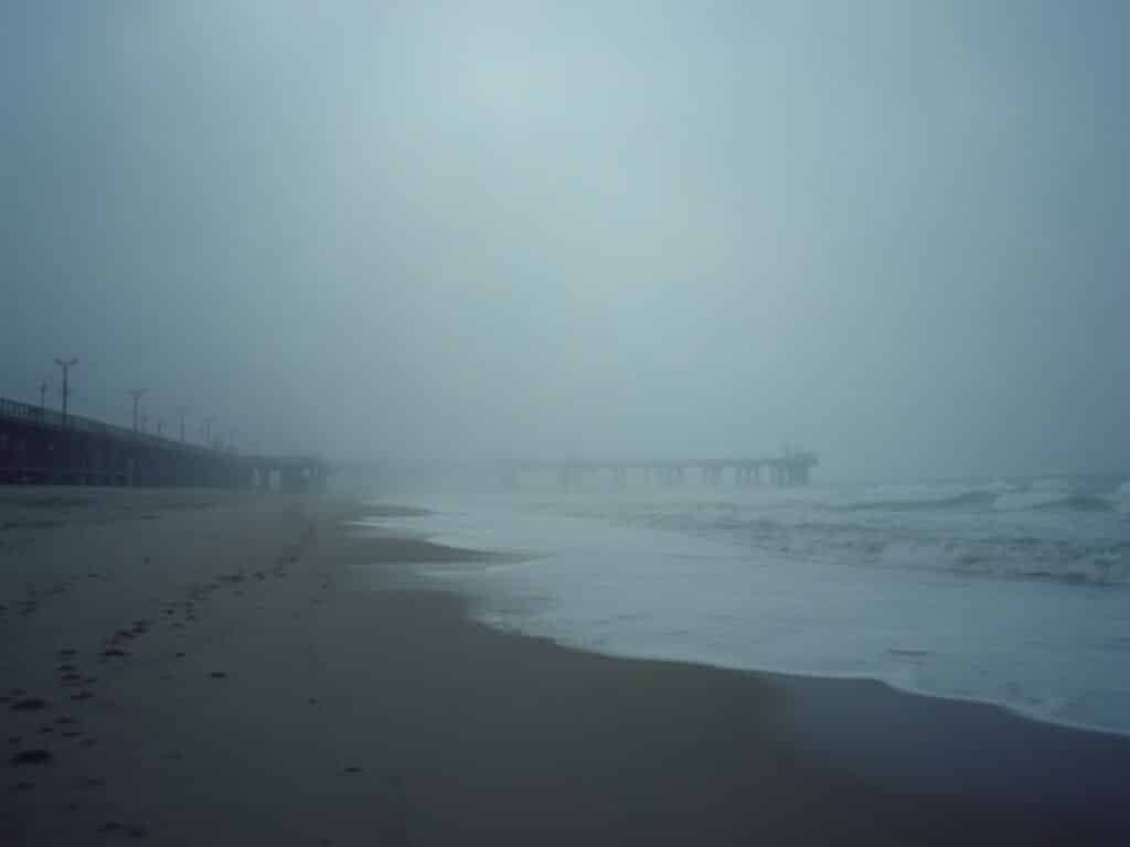 Dawn at Pismo Beach with silhouettes of pier structures barely visible in the dense fog of June gloom