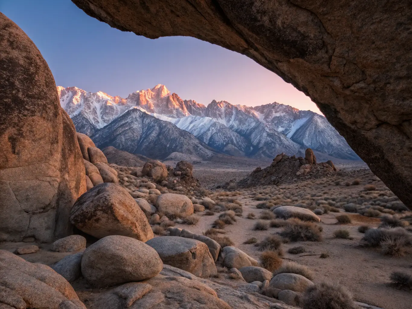 The Best California Road Trips, From Someone Who's Driven Most of Them Dawn view from Alabama Hills showing a granite arch framing snow-dusted Sierra peaks and Mount Whitney glowing pink under golden-hour light.