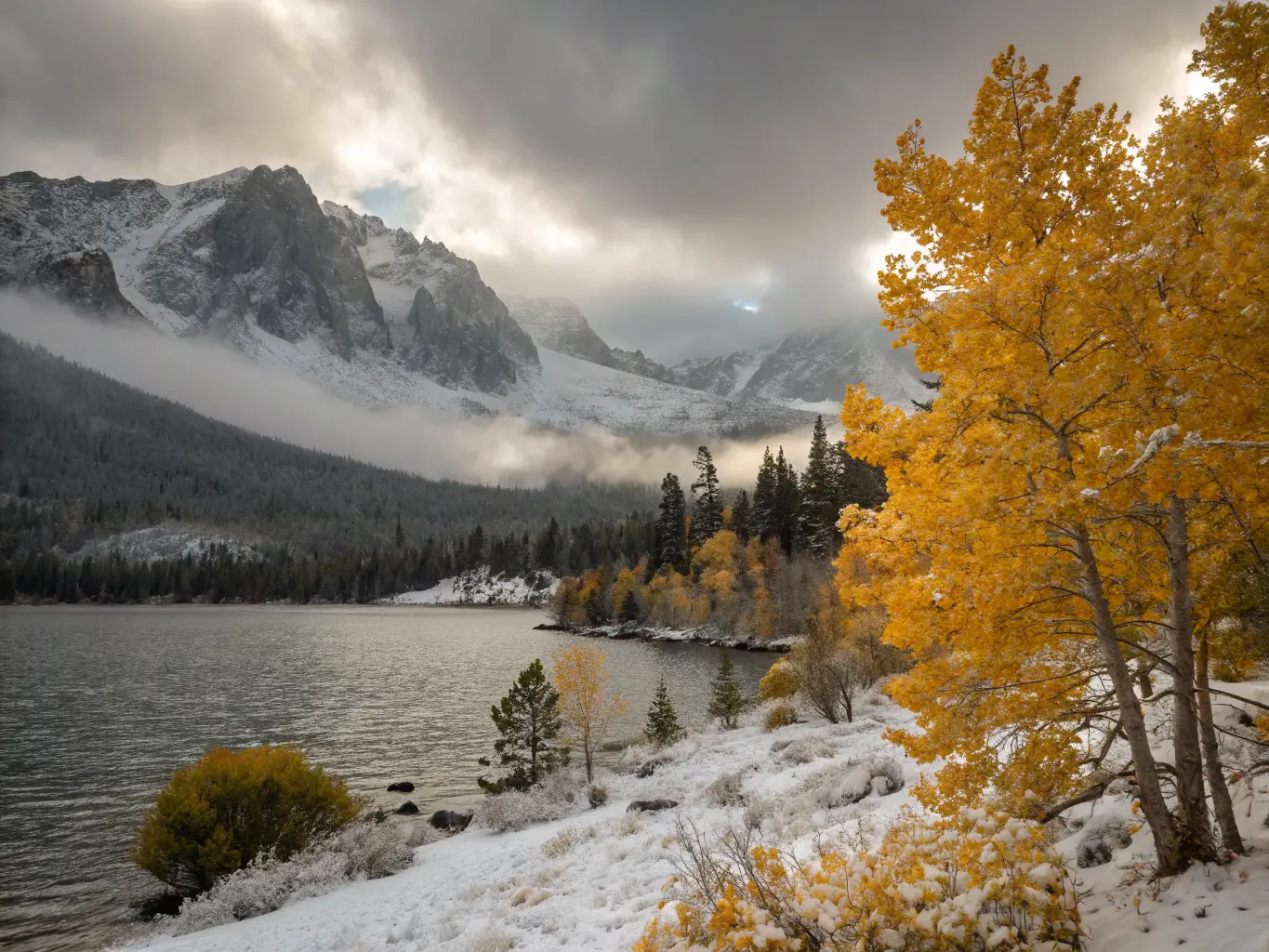October Might Be the Best Month to Visit Mammoth Lakes Snow-dusted golden aspens frame Lake Mary under clearing storm clouds and snow-capped peaks in Mammoth Lakes Basin.
