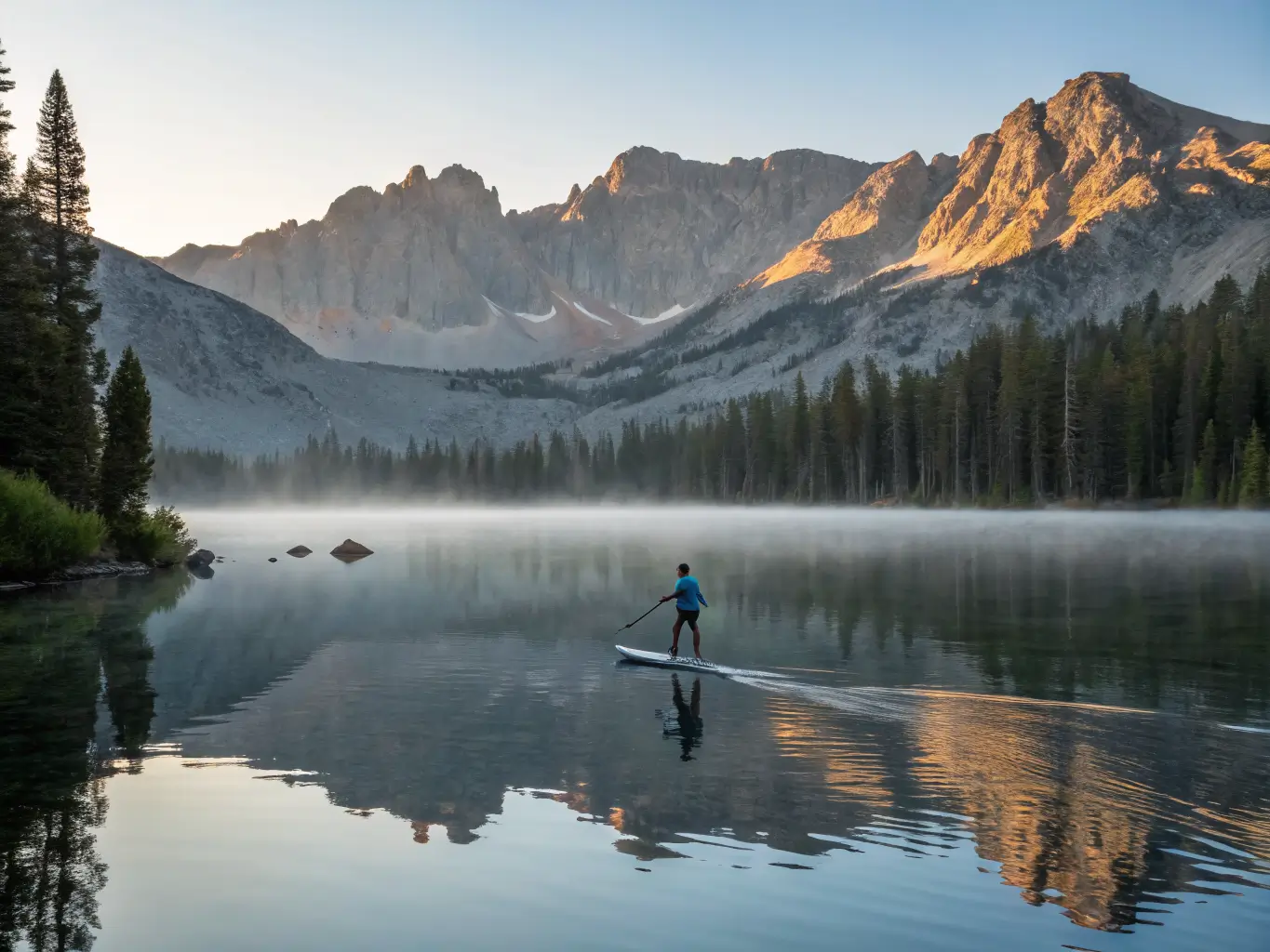 July Is the Month Mammoth Lakes Was Built For Lone paddleboarder gliding across calm Lake Mary at sunrise with Crystal Crag reflected in the still water and mist drifting above the lake.