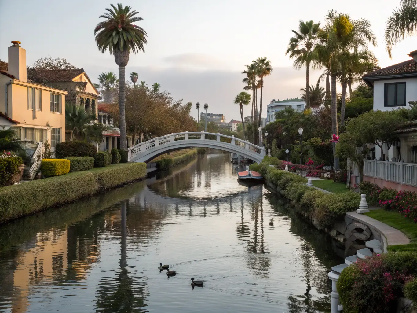 Free Things to Do in Los Angeles If You'd Rather Not Spend a Fortune Peaceful mid-morning view of the Venice Canals with a small arched bridge over calm reflective water, lined by pastel houses, lush gardens, and gliding ducks.